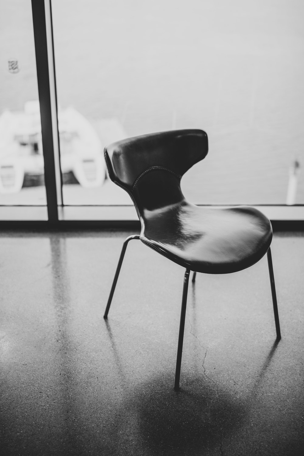 Black-and-white photograph of a polished chair in window light